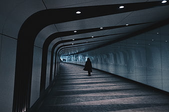 Silhouette of a person walking through a modern curved architectural tunnel