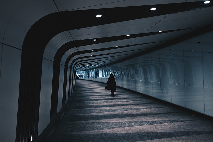 Silhouette of a person walking through a modern curved architectural tunnel