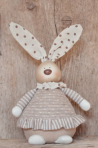 Cute handmade fabric bunny doll on rustic wooden background