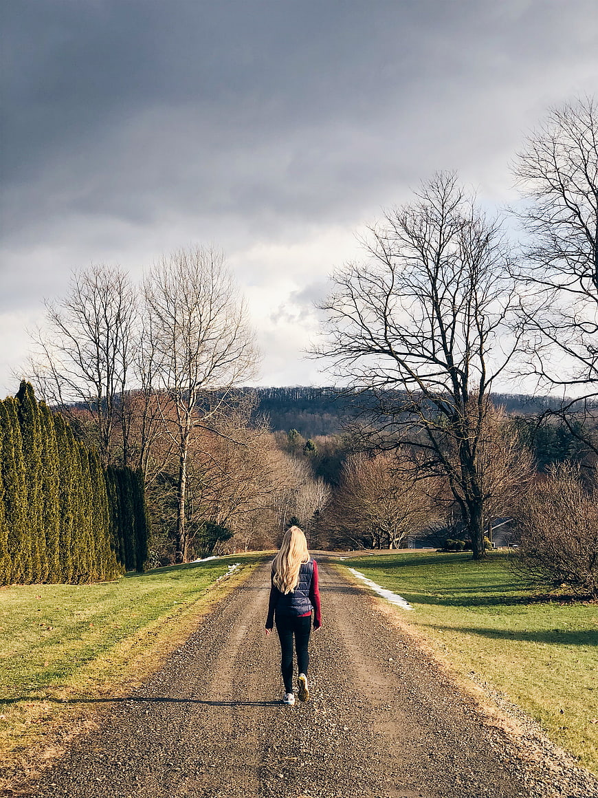Woman Walking Away on Gravel Path in Nature