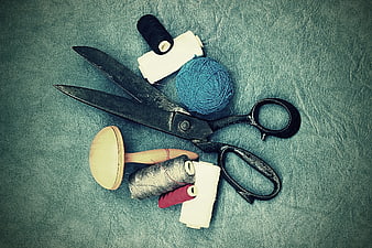 Vintage sewing tools and thread on textured blue background