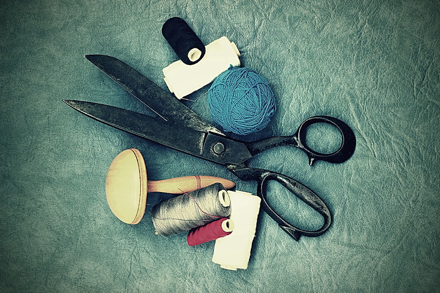 Vintage sewing tools and thread on textured blue background