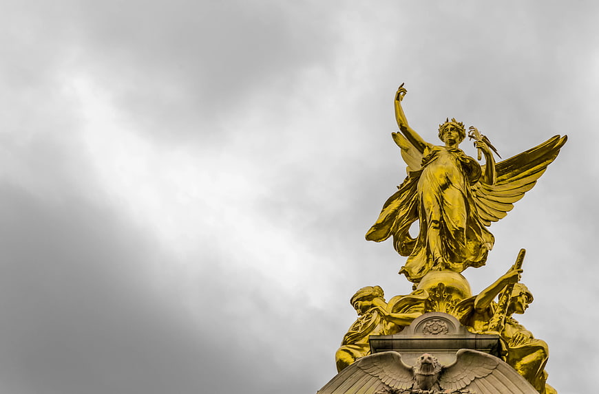 Golden Angel Statue Against Dramatic Grey Cloudy Sky