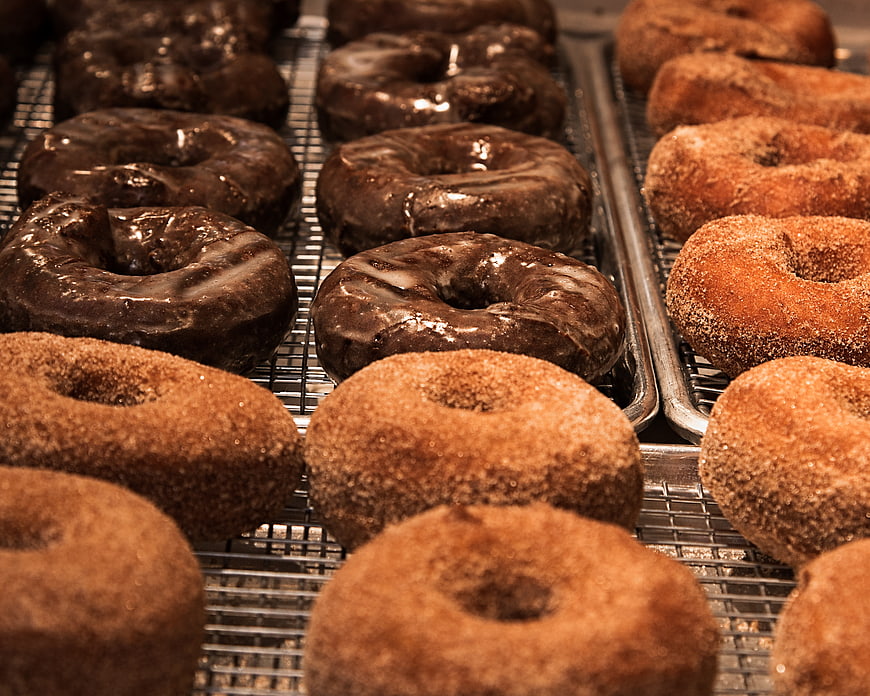 Freshly baked chocolate and cinnamon sugar donuts on cooling racks