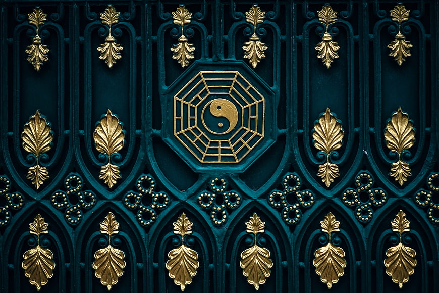 Ornate teal and gold gate featuring a central yin yang and bagua symbol
