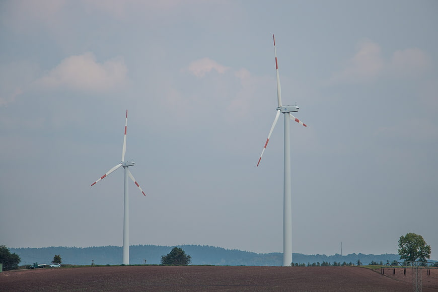 Two wind turbines on a hill against a cloudy sky