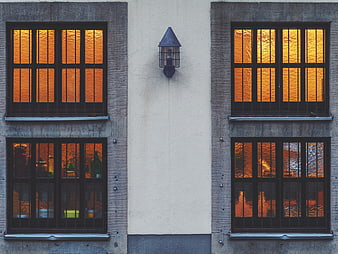 Symmetrical building facade with glowing orange windows and lamp