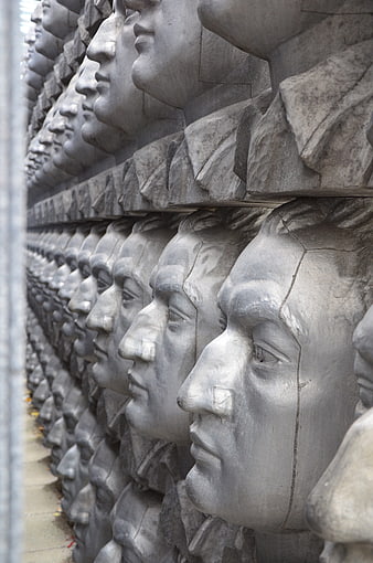 Rows of stone soldier heads in a memorial wall sculpture