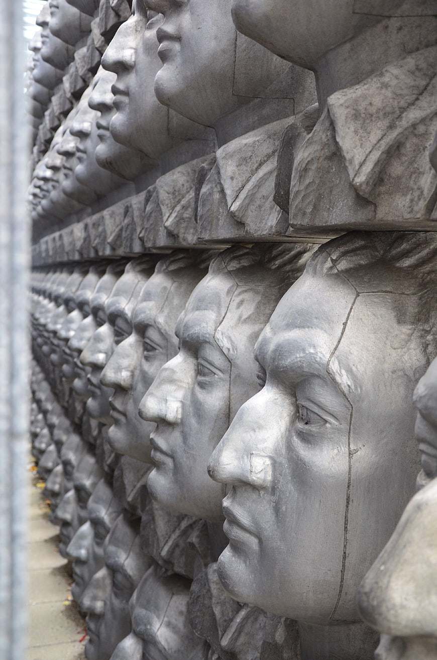 Rows of stone soldier heads in a memorial wall sculpture
