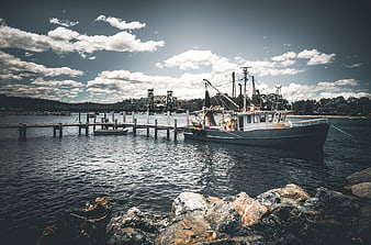 Fishing boat docked at pier with dramatic sky