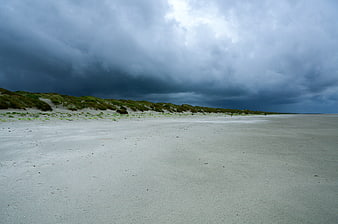 Dramatic storm clouds over empty sandy beach and dunes