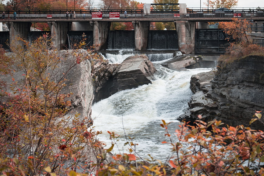 Autumn waterfall flowing under a bridge with colorful foliage