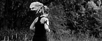 Black and white photo of a woman running outdoors with flying hair