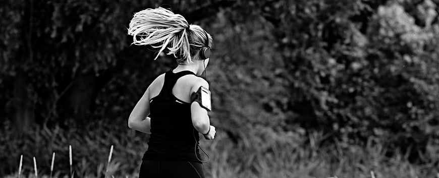 Black and white photo of a woman running outdoors with flying hair
