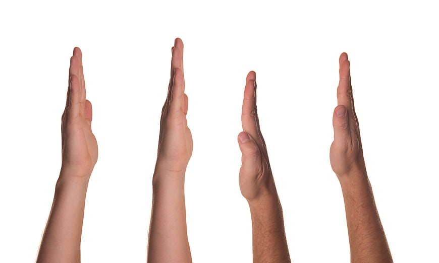 Four raised hands with open palms against white background