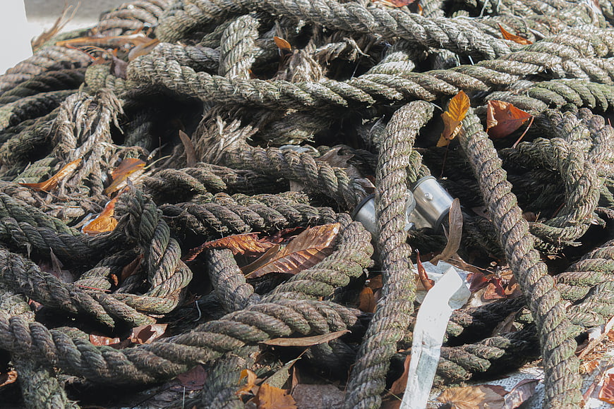 Close-up of weathered marine rope with autumn leaves