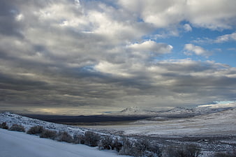 Snowy winter landscape with dramatic clouds and distant mountains