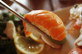 Close-up of Salmon Sushi Held by Chopsticks
