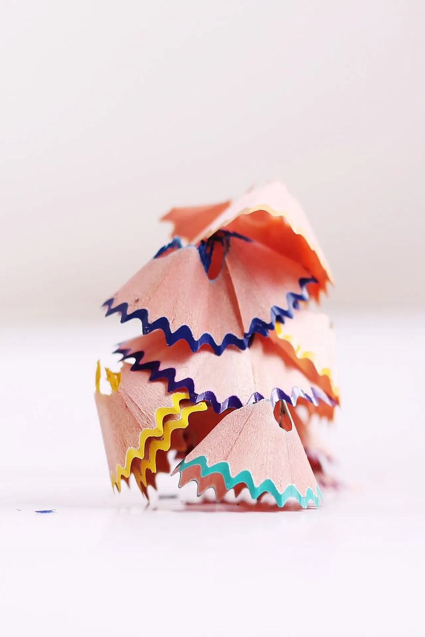 Colorful pencil shavings pile on white background