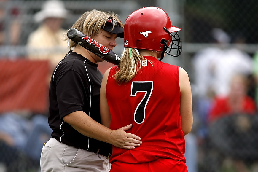 Female Softball Coach Comforting Young Player on the Field