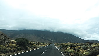 Empty asphalt road leading to misty mountains