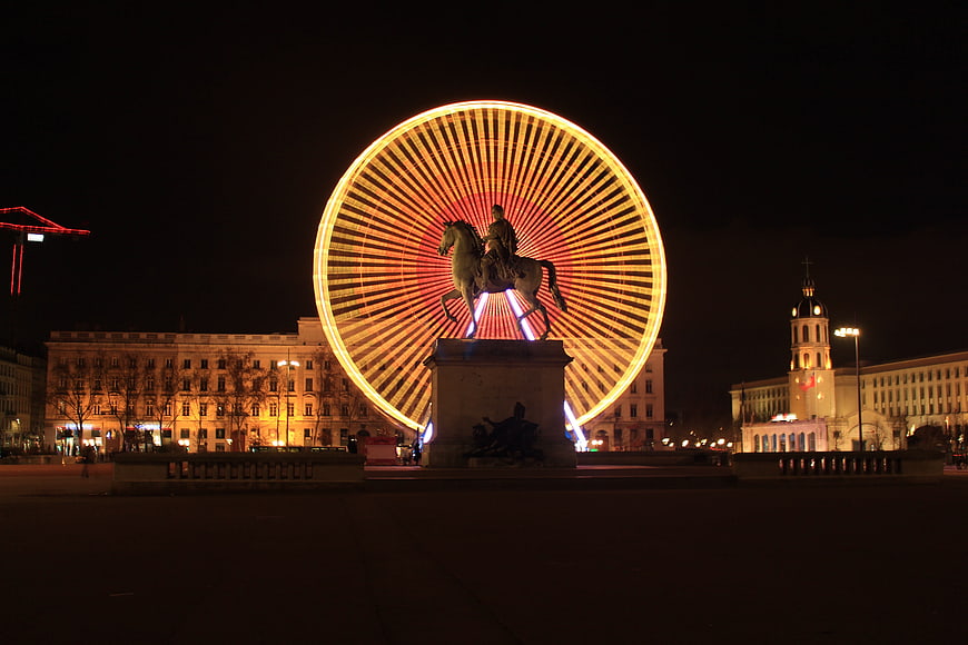 Night view of Place Bellecour in Lyon with illuminated Ferris wheel