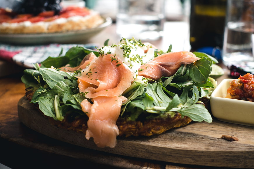 Smoked salmon open sandwich with greens on wooden board