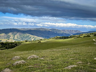 Dramatic Green Rolling Hills and Mountains Under Stormy Sky