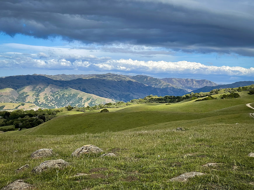 Dramatic Green Rolling Hills and Mountains Under Stormy Sky