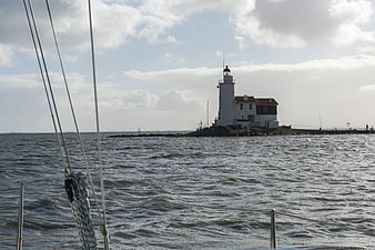 Lighthouse on IJsselmeer viewed from a boat with rigging in foreground