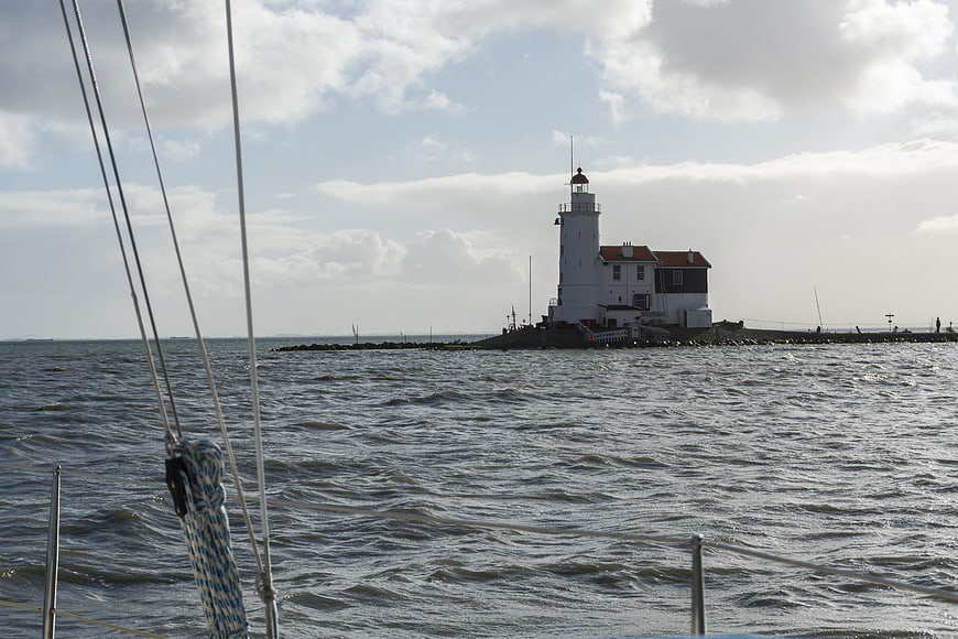 Lighthouse on IJsselmeer viewed from a boat with rigging in foreground