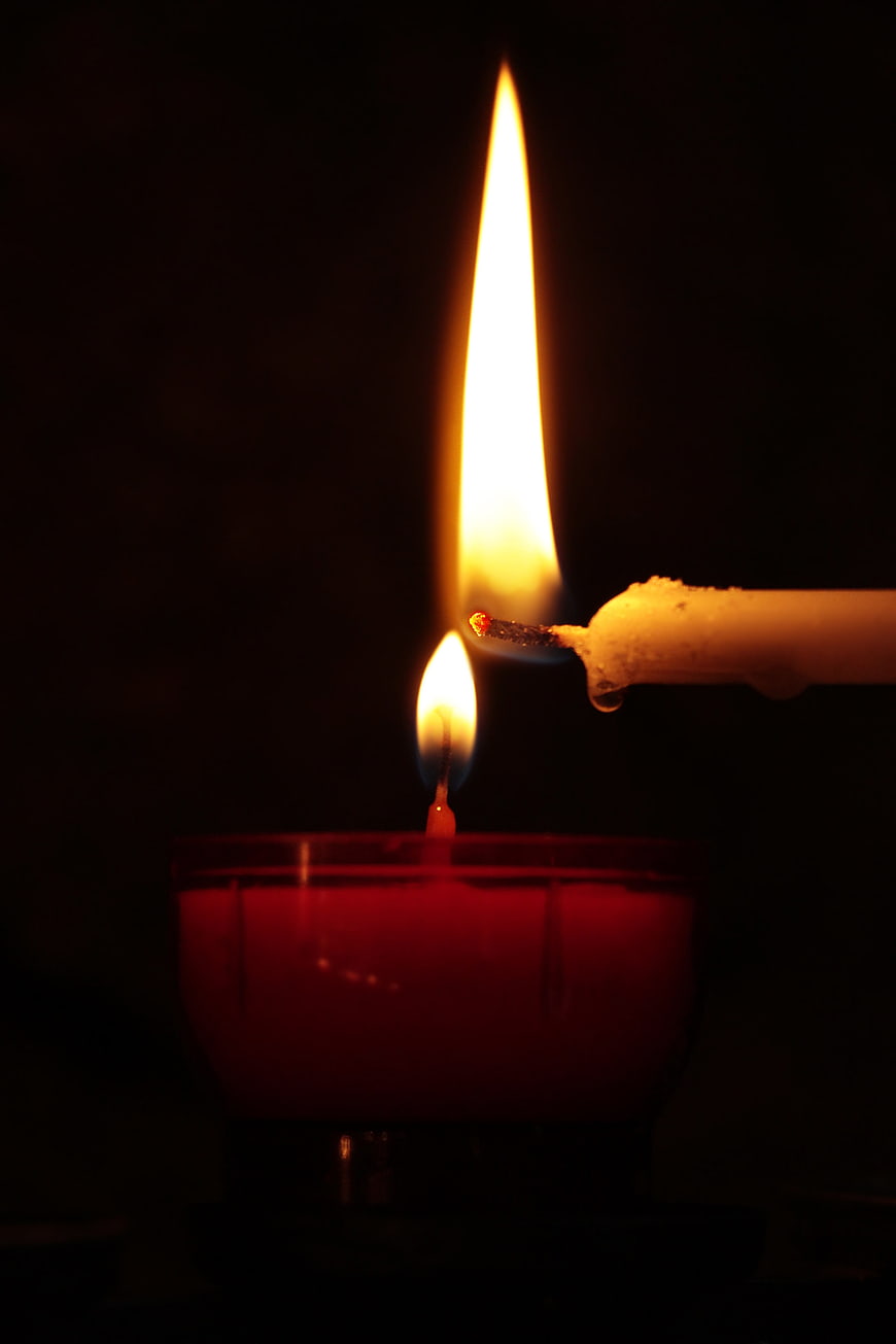 Lighting a red candle flame in the dark