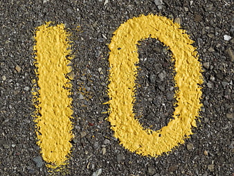 Yellow Number 10 Painted On Rough Asphalt Road Surface