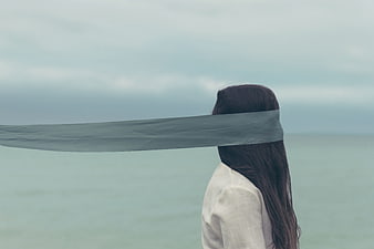 Blindfolded Woman Standing By The Sea With Flowing Fabric