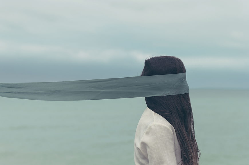 Blindfolded Woman Standing By The Sea With Flowing Fabric