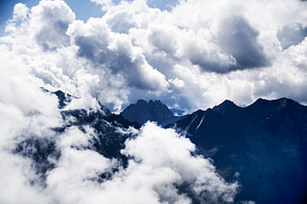 Dramatic mountain peaks emerging through thick white clouds