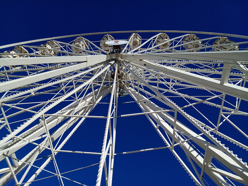 Low angle view of white Ferris wheel against blue sky
