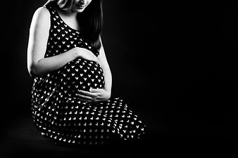Pregnant woman holding belly in black and white