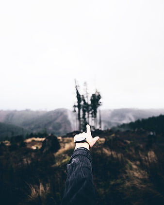 Hand Pointing at Misty Mountain Landscape with Watch
