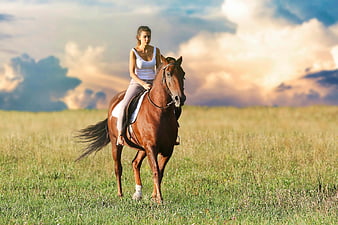 Woman Riding Brown Horse in Green Field at Sunset