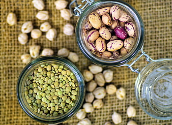 Top view of dried legumes in glass jars on burlap