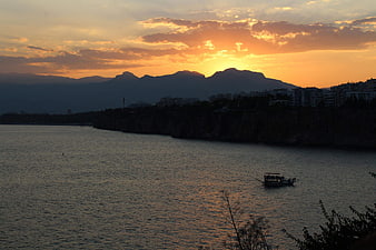 Sunset over coastal city with boat on water