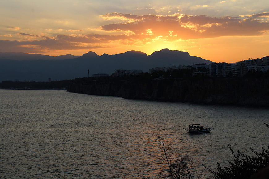 Sunset over coastal city with boat on water