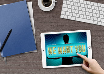 Hand tapping 'We Want You' recruitment message on tablet in office workspace