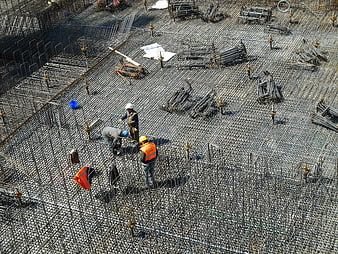 Construction workers installing rebar grid on building site