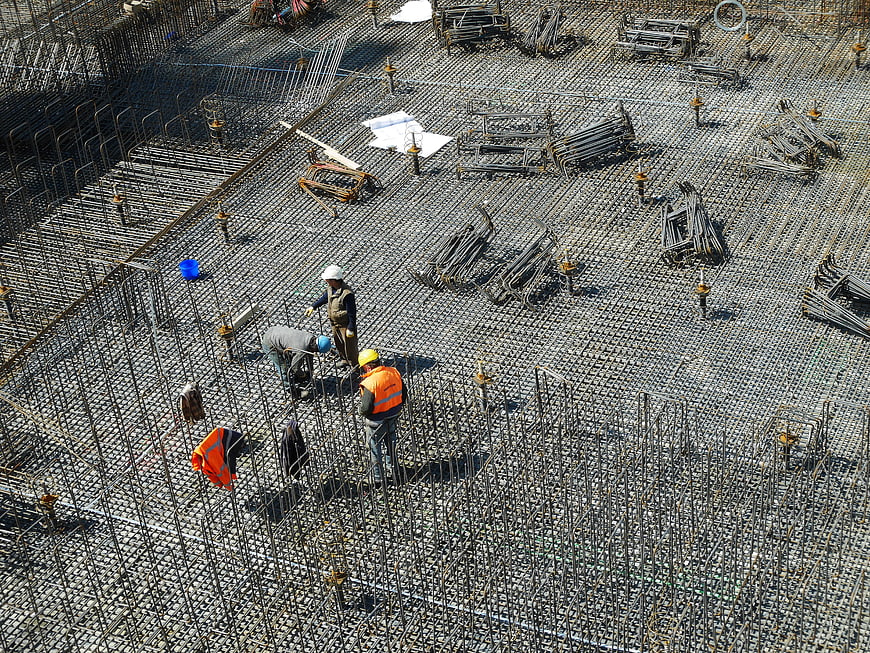 Construction workers installing rebar grid on building site