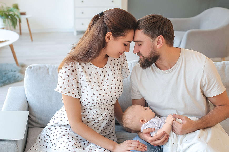 Young loving family with baby on sofa