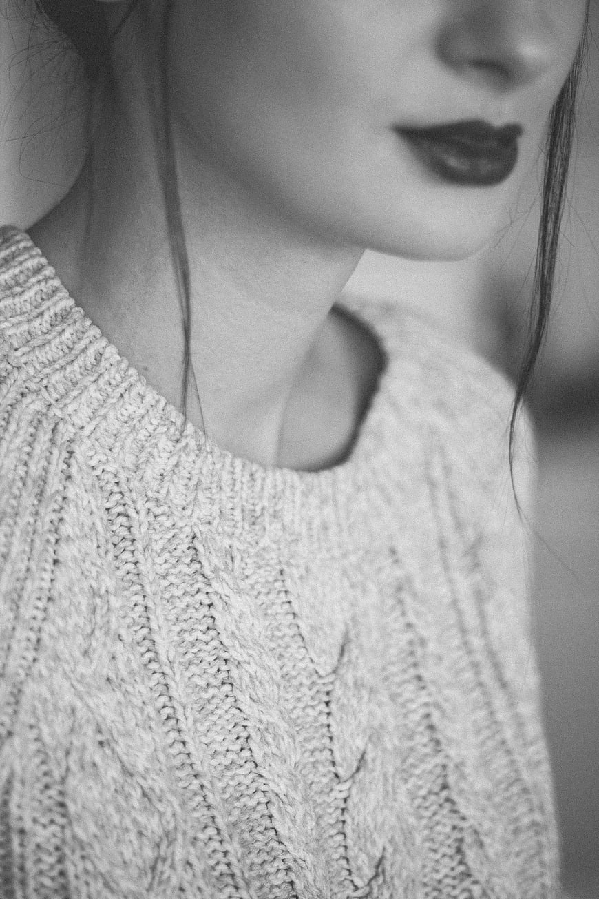 Close-up of woman in cable knit sweater with dark lipstick
