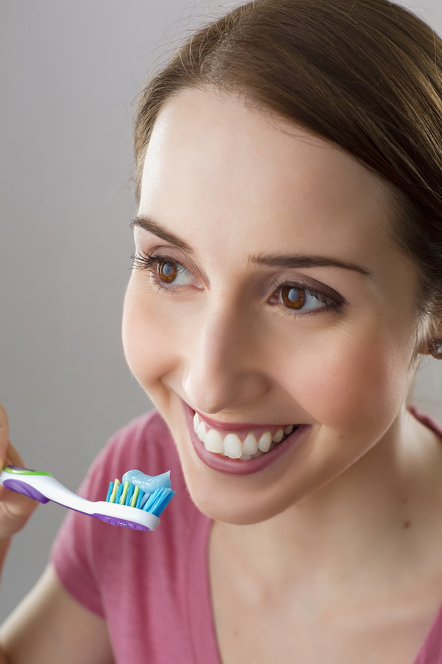 Smiling Woman Holding Toothbrush with Toothpaste