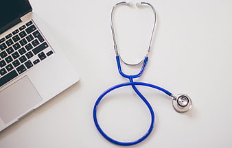Blue Stethoscope and Laptop on White Desk